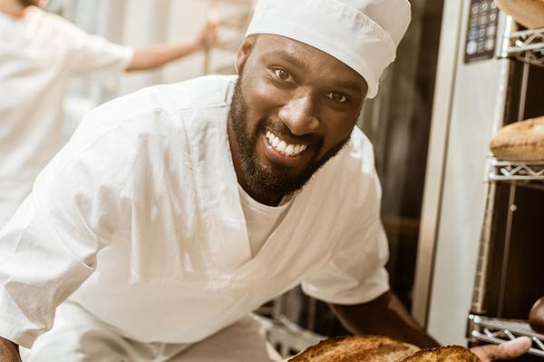 Man holding a batch of freshly baked bread.