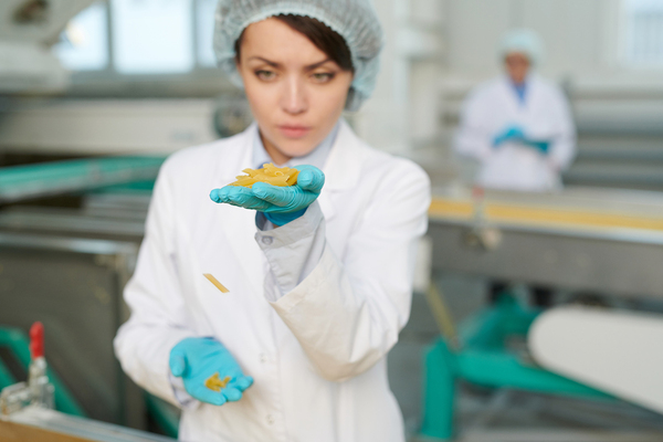 Woman inspecting a food item in a manufacturing plant.