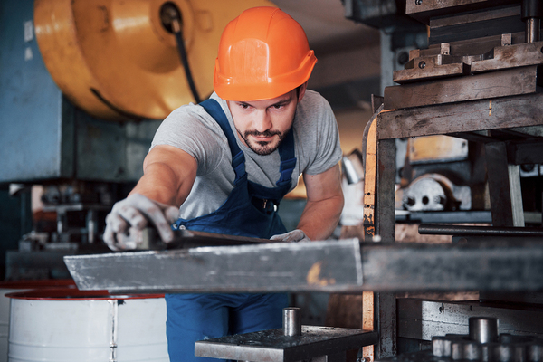 Technician wearing an orange hardhat while working with machinery.