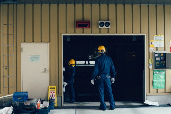 Technicians standing outside a garage door.